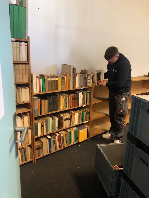 Ein junge Möbelträger sortierte die Bücher schön auf Kante ein Ein junge Möbelträger sortierte die Bücher schön auf Kante ein